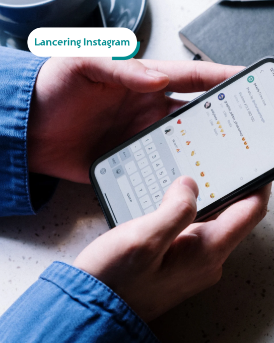 Iemand houdt een smartphone vast en typt een reactie met emoji's op Instagram. (vergroot foto)