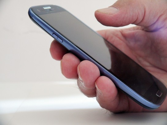 Een hand houdt een smartphone vast met een zwart scherm. (vergroot foto)