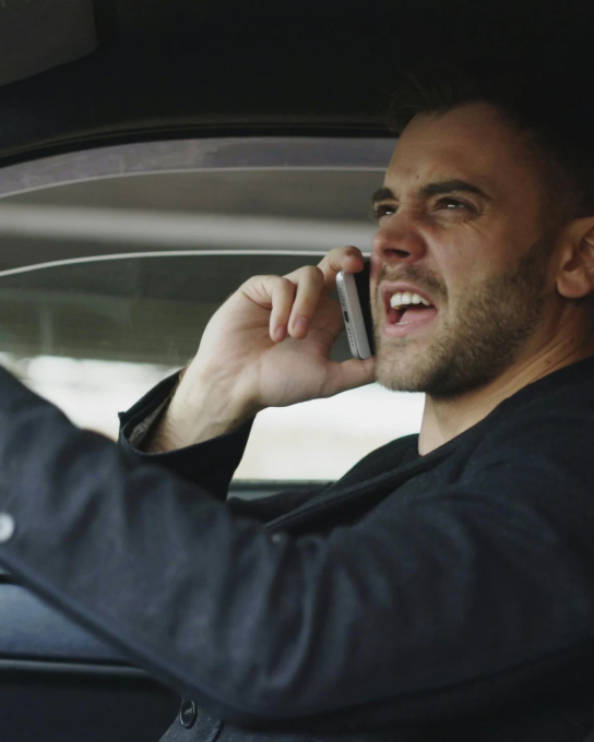 Man in auto praat boos en geïrriteerd op mobiele telefoon. (vergroot foto)